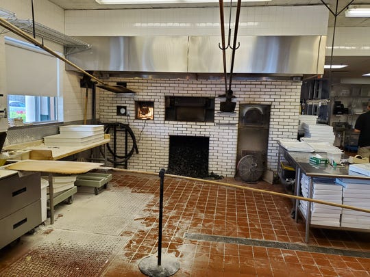 Every step of production from rolling out the dough on a floured surface to cooking in the coal ovens to slicing and boxing, is done in full view of customers. Because the ovens are so hot, the require custom extra long handled pizza peels, hanging from hooks.